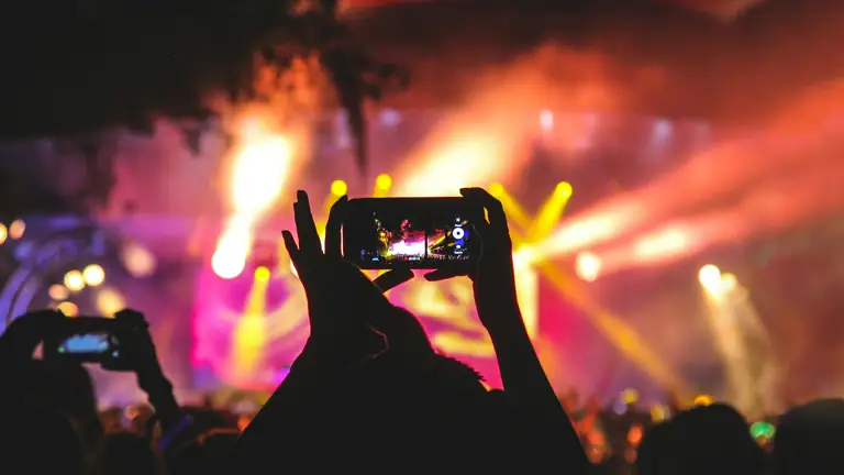 A fan holding up a phone to film the stage lights.
