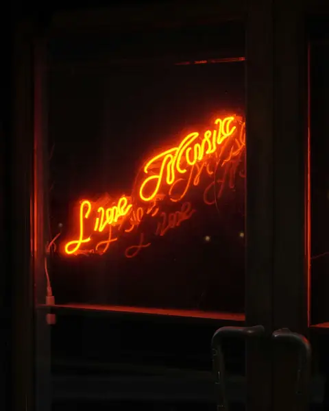 A glowing Live Music neon sign in a venue window.